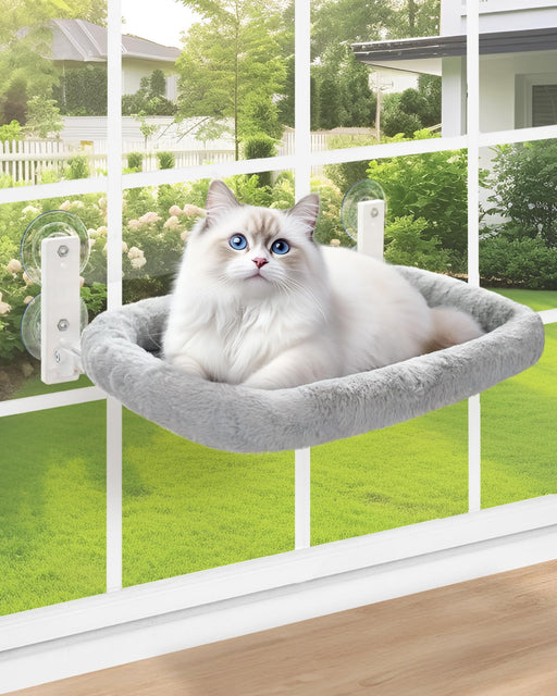 White cat with blue eyes relaxing in gray plush window perch with suction cup mounts