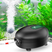 Black aquarium air pump with green button in planted fish tank with bubbles and small fish
