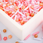 Square white foam ball pit filled with pink orange and white star shaped plastic balls