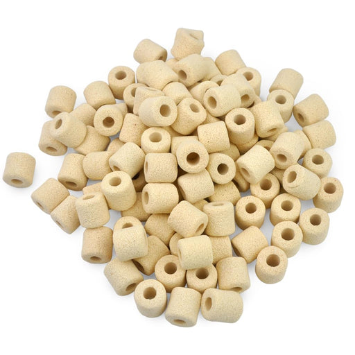 Scattered pile of beige ceramic ring filter media showing cylindrical tubes with hollow centers