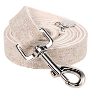 Beige cotton hemp dog leash with metal swivel clasp coiled on white background