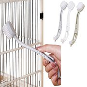 Hand holding white bird cage cleaning brush with dual brush heads and long curved handle