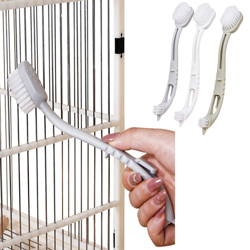 White bird cage cleaning brush with dual heads being held near bamboo bird cage