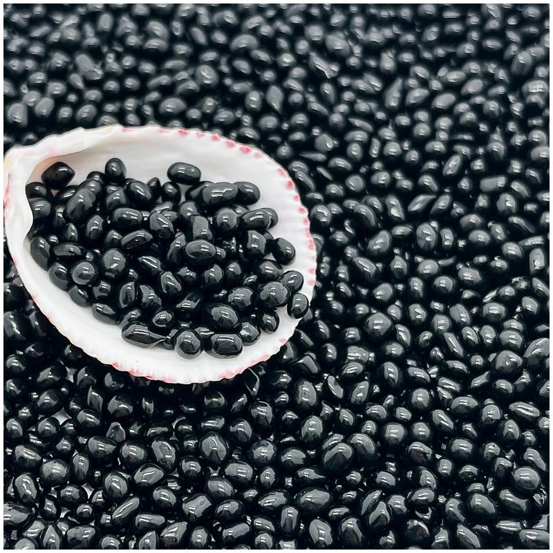 Black glass aquarium substrate sand scattered with white shell bowl containing sample of beads