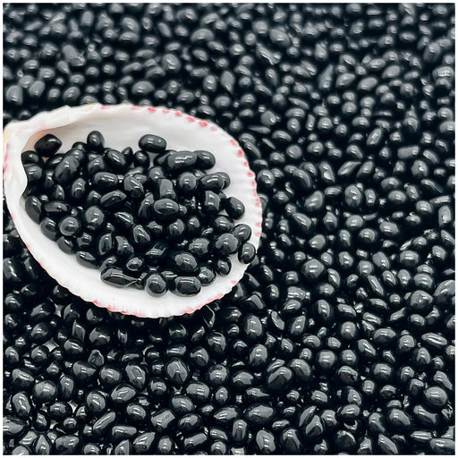 Black glass aquarium substrate sand scattered with white shell bowl containing sample of beads