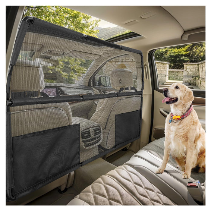 Golden retriever sitting behind black mesh car dog safety barrier in vehicle backseat