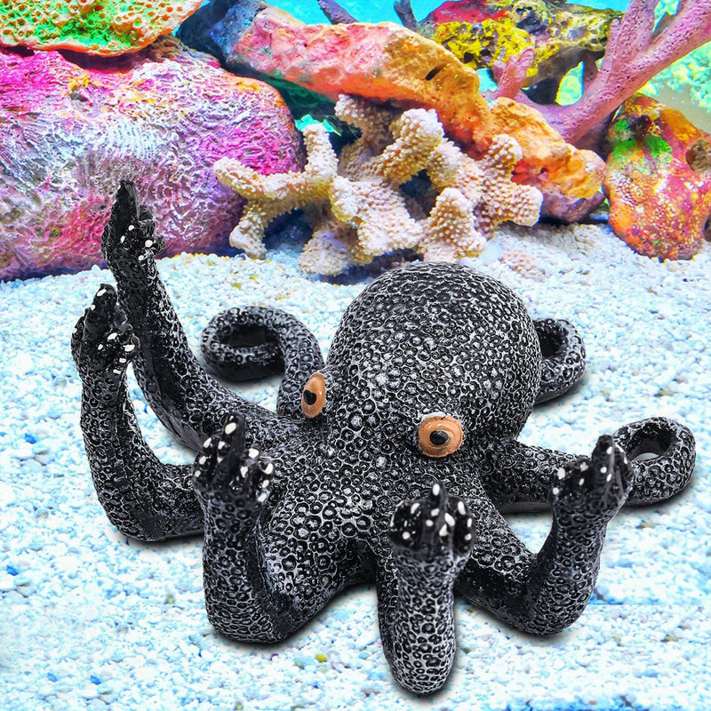 Black textured octopus aquarium decoration with orange eyes on sandy bottom with colorful coral