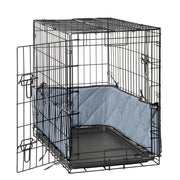 Black wire dog crate with blue quilted bumper pads installed along the walls and door open