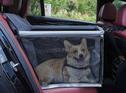Two dogs behind black mesh car barrier in vehicle backseat with red leather interior