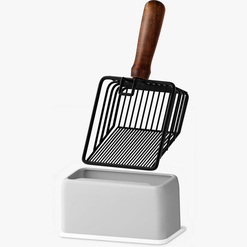Black wire cat litter scoop with wooden handle standing in white ceramic holder base