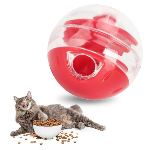 Red and clear puzzle ball toy with tabby cat eating kibble from white bowl nearby