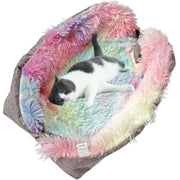 Gray and white cat lying comfortably in colorful tie-dye faux fur pet bed with rainbow colors
