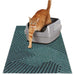 Orange tabby cat stepping out of gray litter box on teal geometric patterned mat