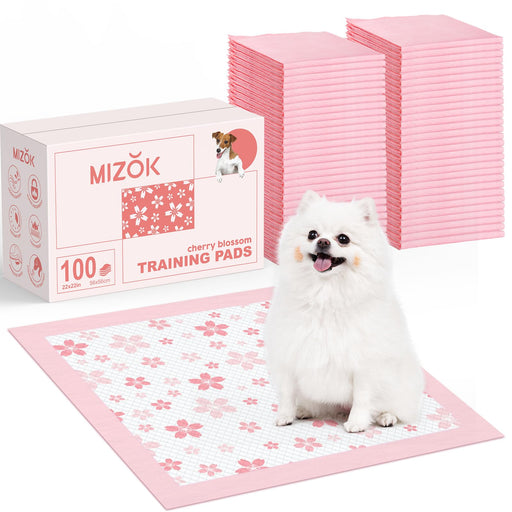 White fluffy dog sitting on pink cherry blossom training pad with product box and pad stacks