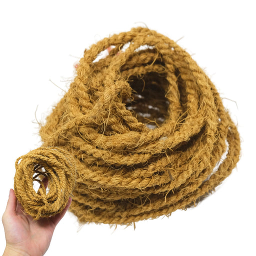 Hand holding coiled natural coconut fiber rope showing texture and brown fibrous material