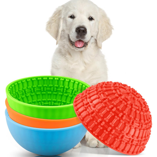 Golden retriever puppy with colorful silicone lick bowls and red textured ball on white background