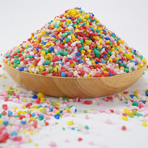 Colorful mini gravel rocks piled high in wooden bowl with scattered pieces on white surface