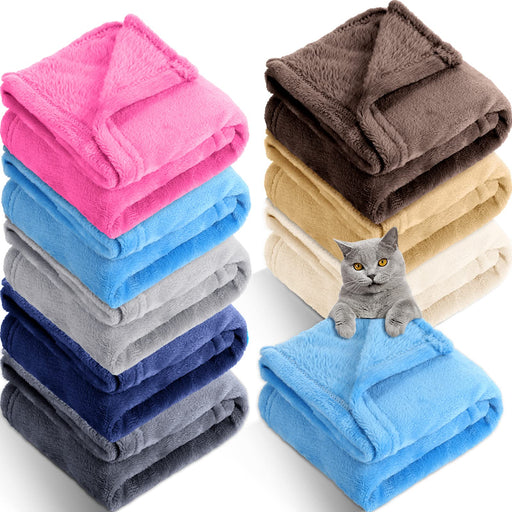 Colorful fleece pet blankets stacked in two piles with gray cat sitting on blue blanket