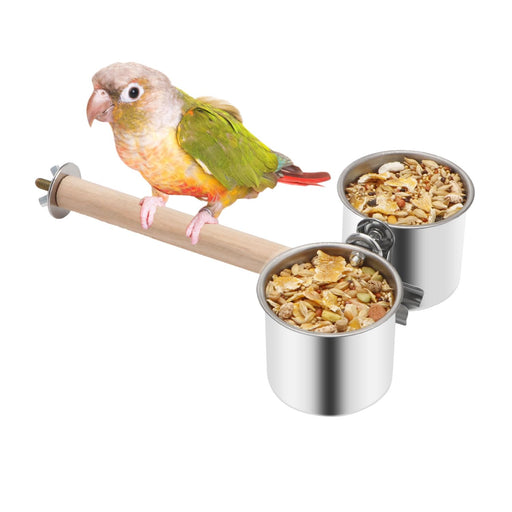 Green and peach conure perched on natural wood branch with two stainless steel food bowls