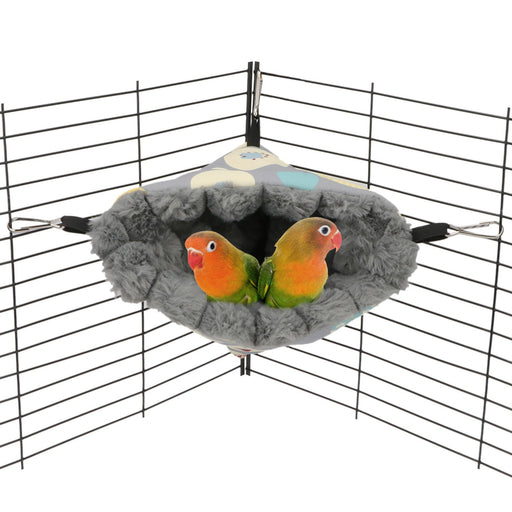 Gray fuzzy bird hammock hanging in cage corner with two orange and green lovebirds snuggled inside