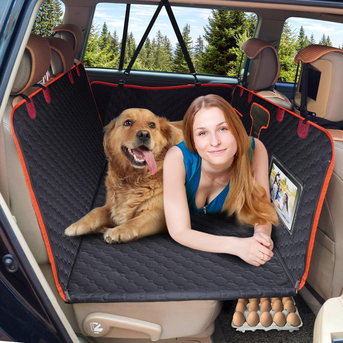 Woman and golden retriever sitting together on black quilted dog car seat cover in SUV