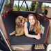 Woman and golden retriever sitting together on black quilted dog car seat cover in SUV