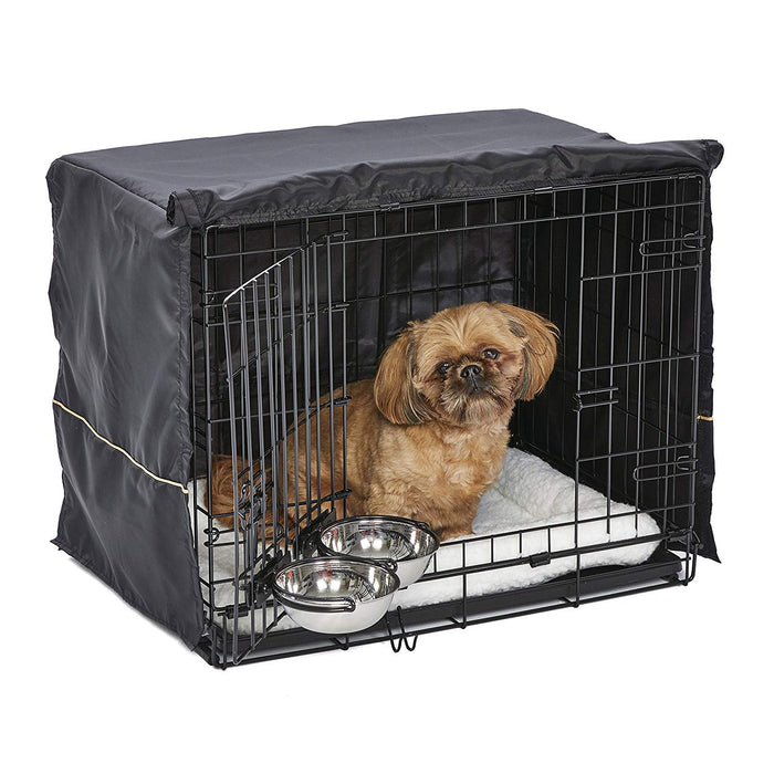 Small tan dog sitting inside black wire crate with dark cover, white bedding and metal bowls