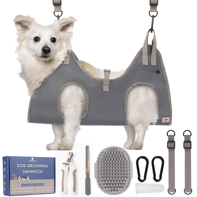 White fluffy dog wearing gray grooming hammock sling with nail clippers and grooming tools below
