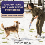 Woman playing with dog in snow using Primens paw balm for winter protection
