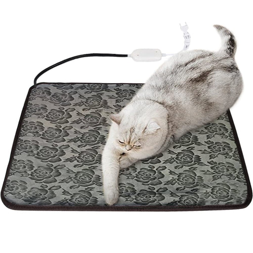 Gray tabby cat lying on floral patterned electric heating mat with USB cord and controller