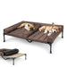Two dogs sleeping on brown elevated double dog bed with padded cushions and black metal frame