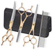 Five gold-colored pet grooming scissors and comb with black carrying case on white background