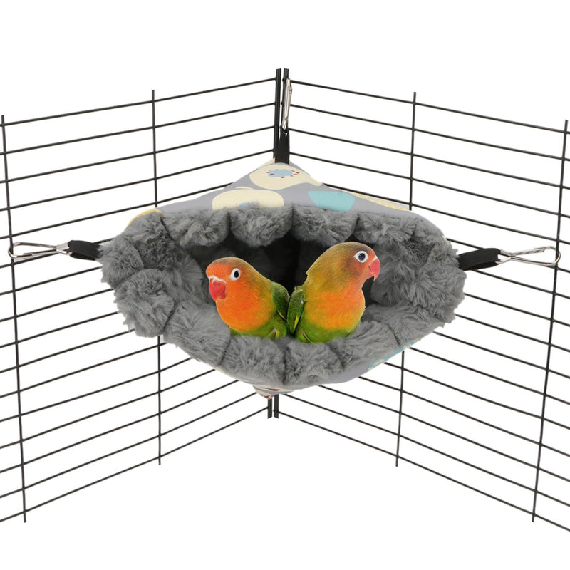 Two orange and green lovebirds sitting together in a gray fuzzy corner hammock nest inside cage
