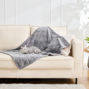 Gray textured coral fleece blanket draped on beige sofa with tabby cat lying on it