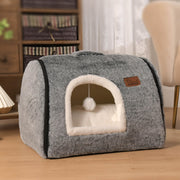Gray enclosed cave cat bed with white interior cushion and hanging pom-pom toy