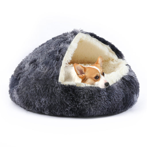 Small orange and white Corgi dog nestled inside gray hooded cave pet bed with cream interior