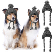 Two dogs wearing gray knitted winter hats with pom-poms and braided ear flaps on white background