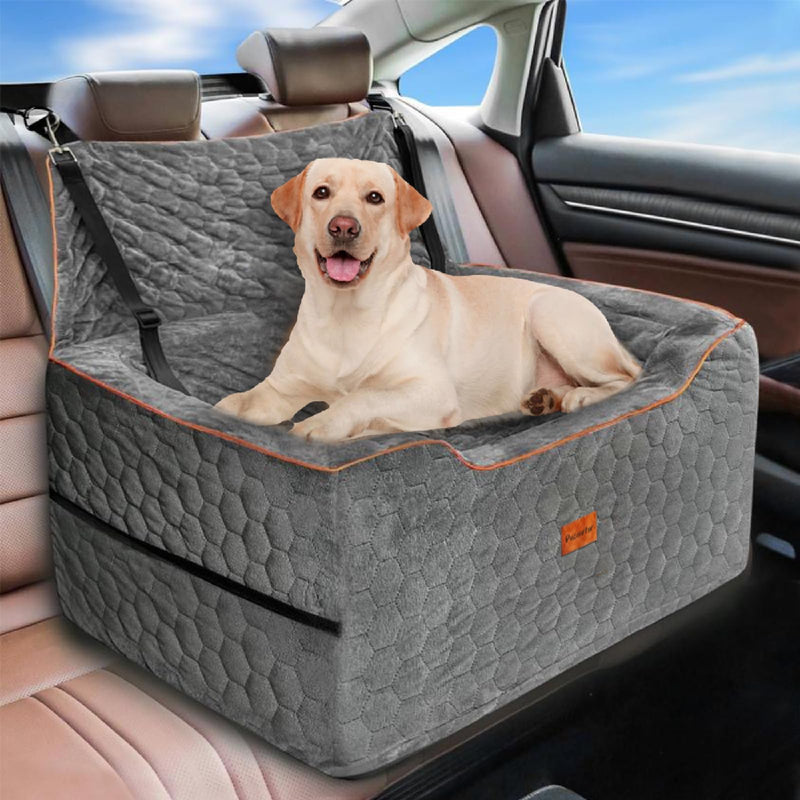 Yellow Labrador sitting in gray quilted dog car seat with orange trim in vehicle backseat