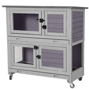 Gray wooden two-story rabbit hutch with wire mesh doors and pull-out trays on wheels