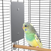 Gray USB heating pad mounted in bird cage with colorful budgerigar perched on wooden dowel