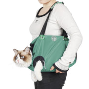 Woman wearing green cat sling carrier with Siamese cat's head and paw sticking out of opening