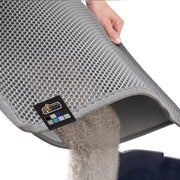Hand lifting gray honeycomb cat litter mat showing litter being sifted through holes