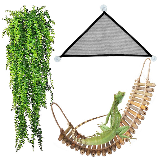 Green iguana resting on bamboo rope bridge with artificial vine plant and triangular hammock