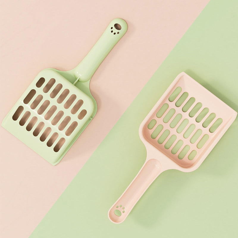Two cat litter scoops in mint green and pink colors with perforated design on pastel background