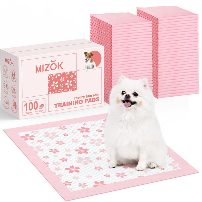 White Pomeranian dog sitting on pink cherry blossom training pad with product packaging and stacks