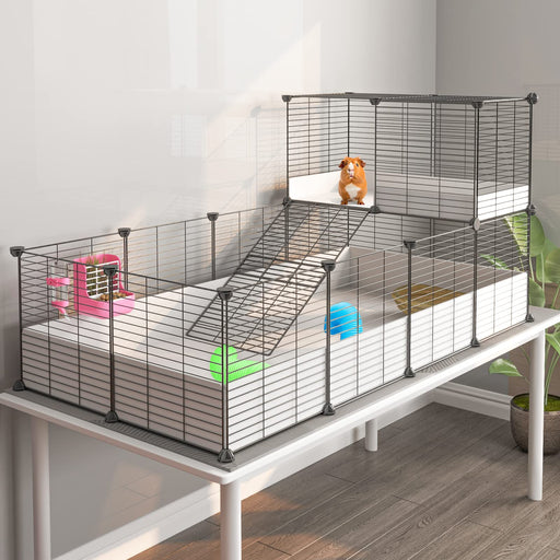 Multi-level guinea pig cage with ramp, orange guinea pig on upper level, colorful accessories
