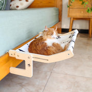 Orange and white cat relaxing in wooden hammock with fish pattern fabric near blue sofa