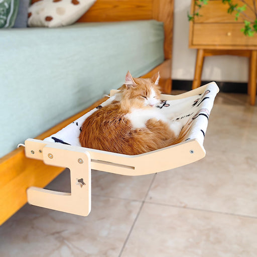 Orange and white cat relaxing in wooden hammock with fish pattern fabric near blue sofa