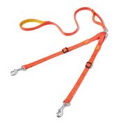 Orange dual dog leash with metal clips and adjustable straps laid out on white background