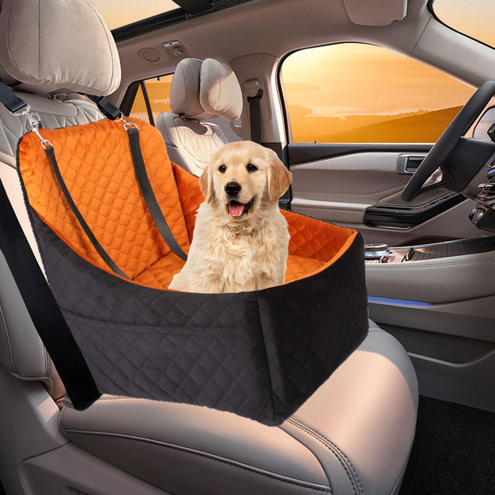 Golden retriever puppy sitting in orange and black quilted elevated car seat inside vehicle